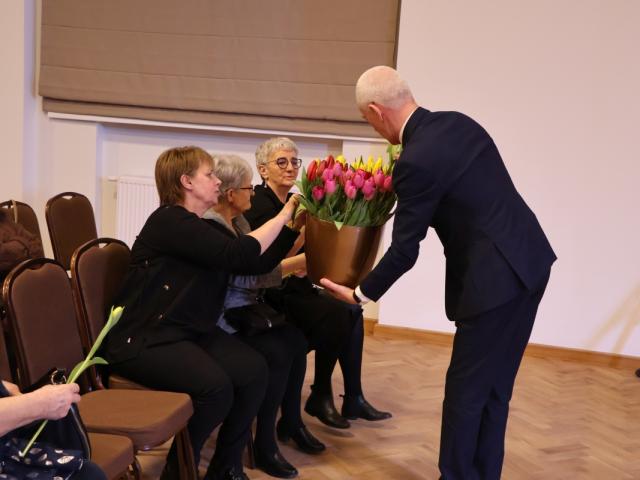 Wójt gminy Włoszakowice Robert Kasperczak wręcza tulipany obecnym kobietom